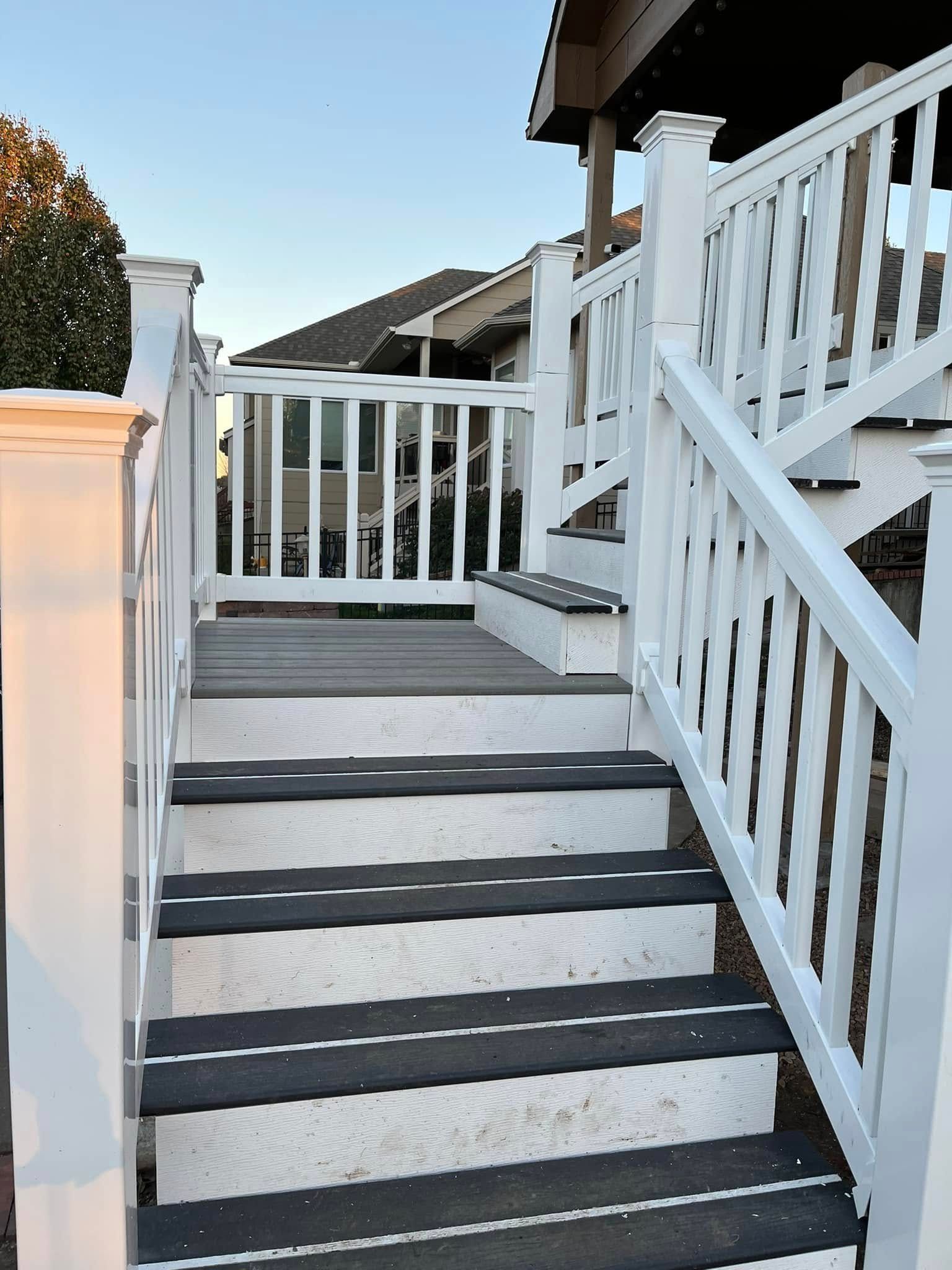 White wooden staircase with black non-slip strips leads to a fenced deck area.