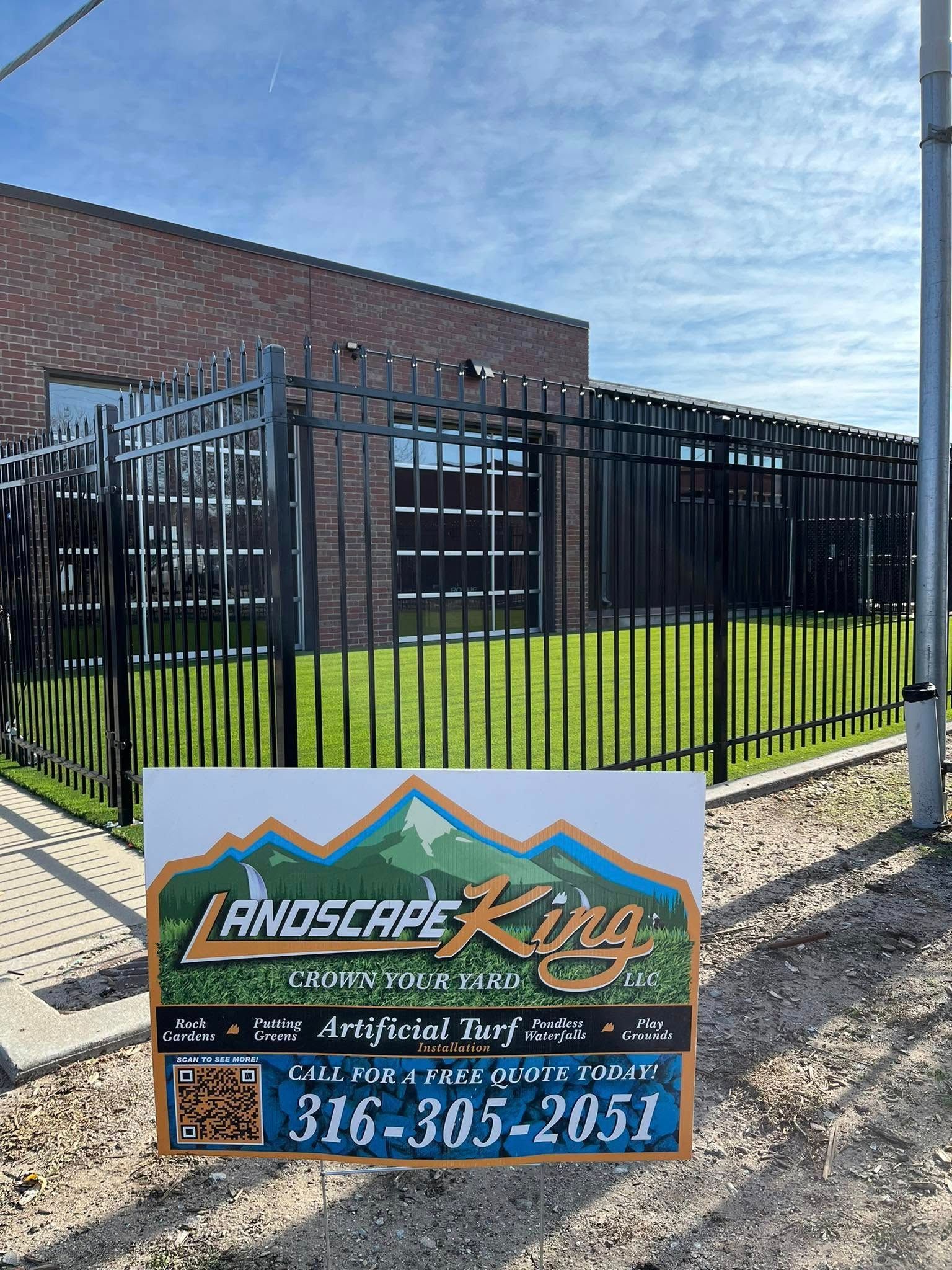 Black iron fence surrounds a building with a Landscape King sign in front.