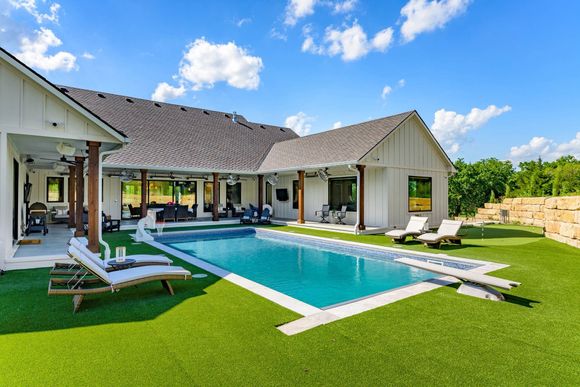 Green lawn with a dark gray path and a wooden fence, under a sunny blue sky.