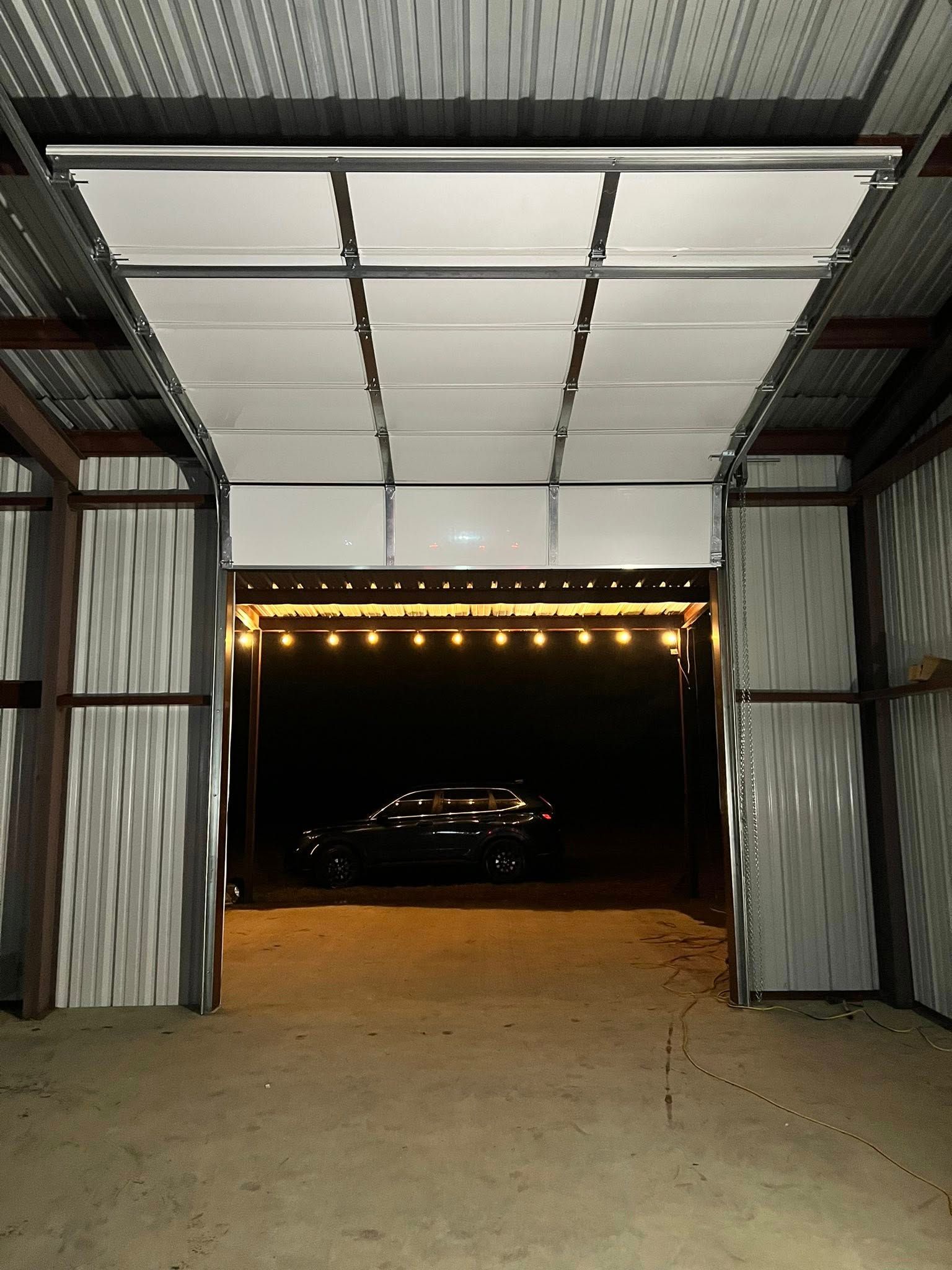 Open carport entrance with corrugated metal walls and roof, string lights, and a dark car.