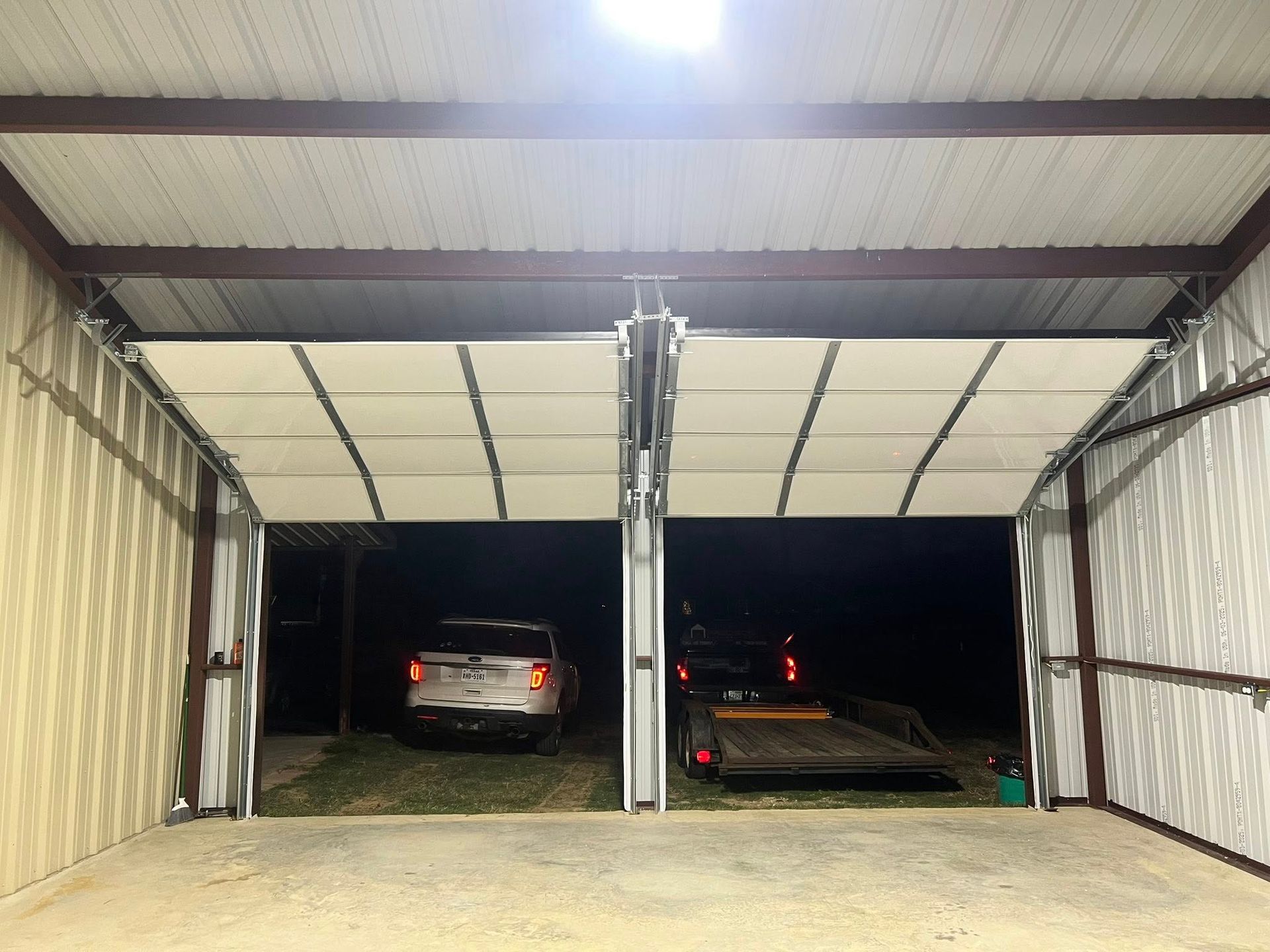 Metal garage with two open doors, two vehicles inside.
