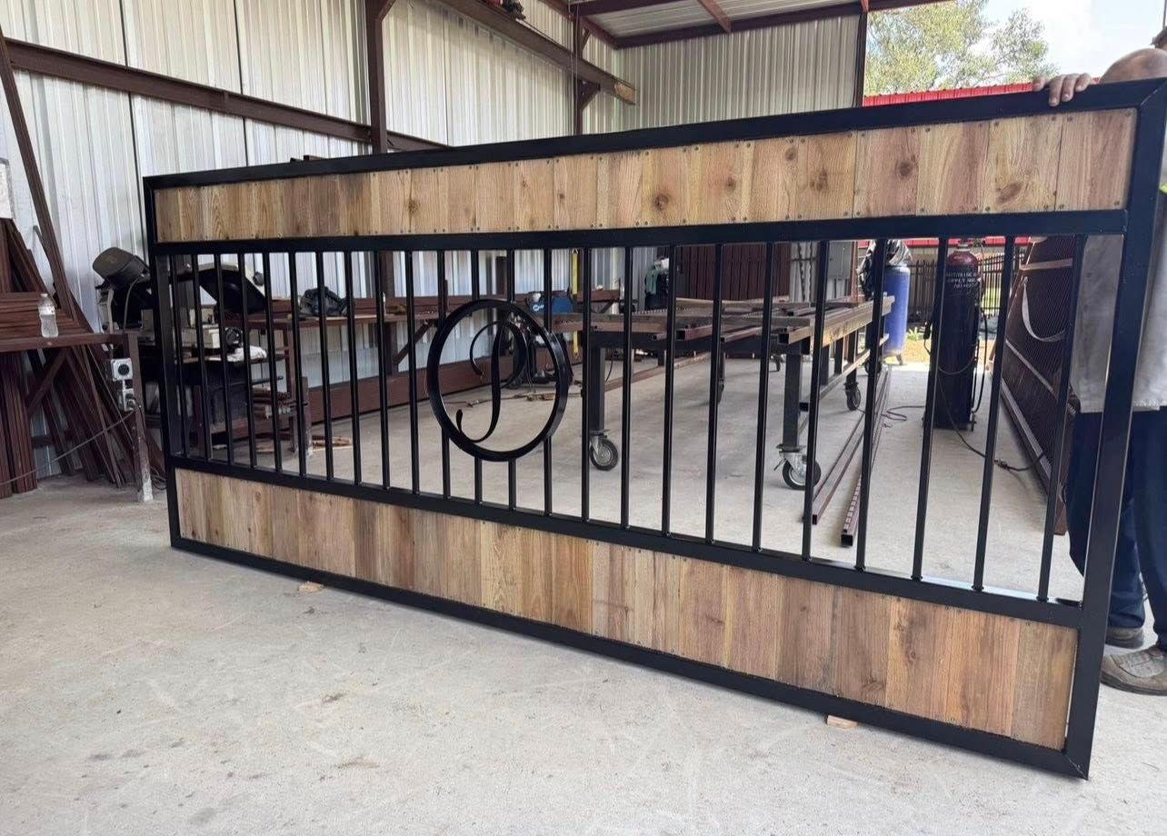 Large metal and wood gate with vertical bars and a circular design, indoors.