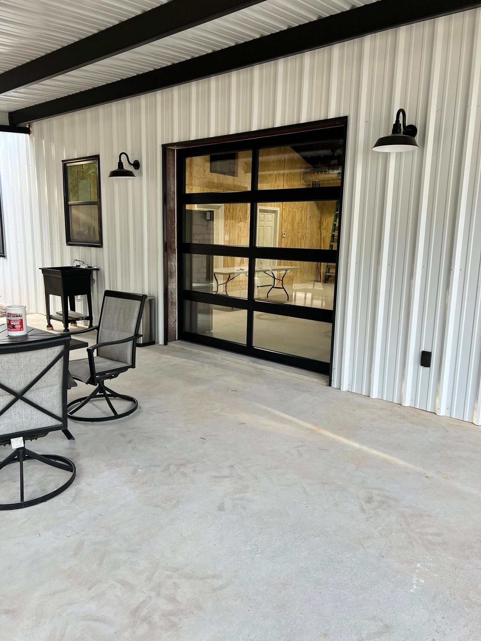 Patio with a glass garage door, metal siding, black trim, and outdoor furniture.