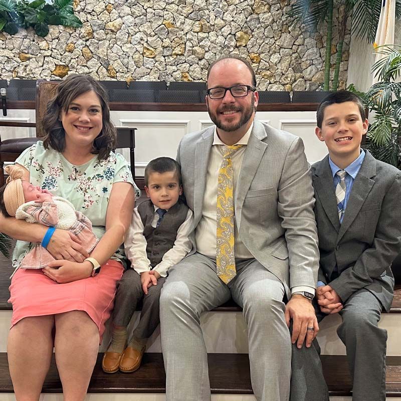 Family of five sits on steps: mom, dad, and three children, two boys and a baby.