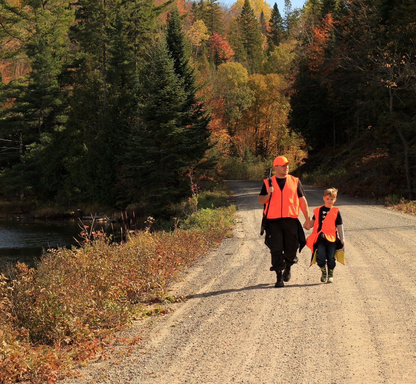 A man and a boy are walking down a dirt road