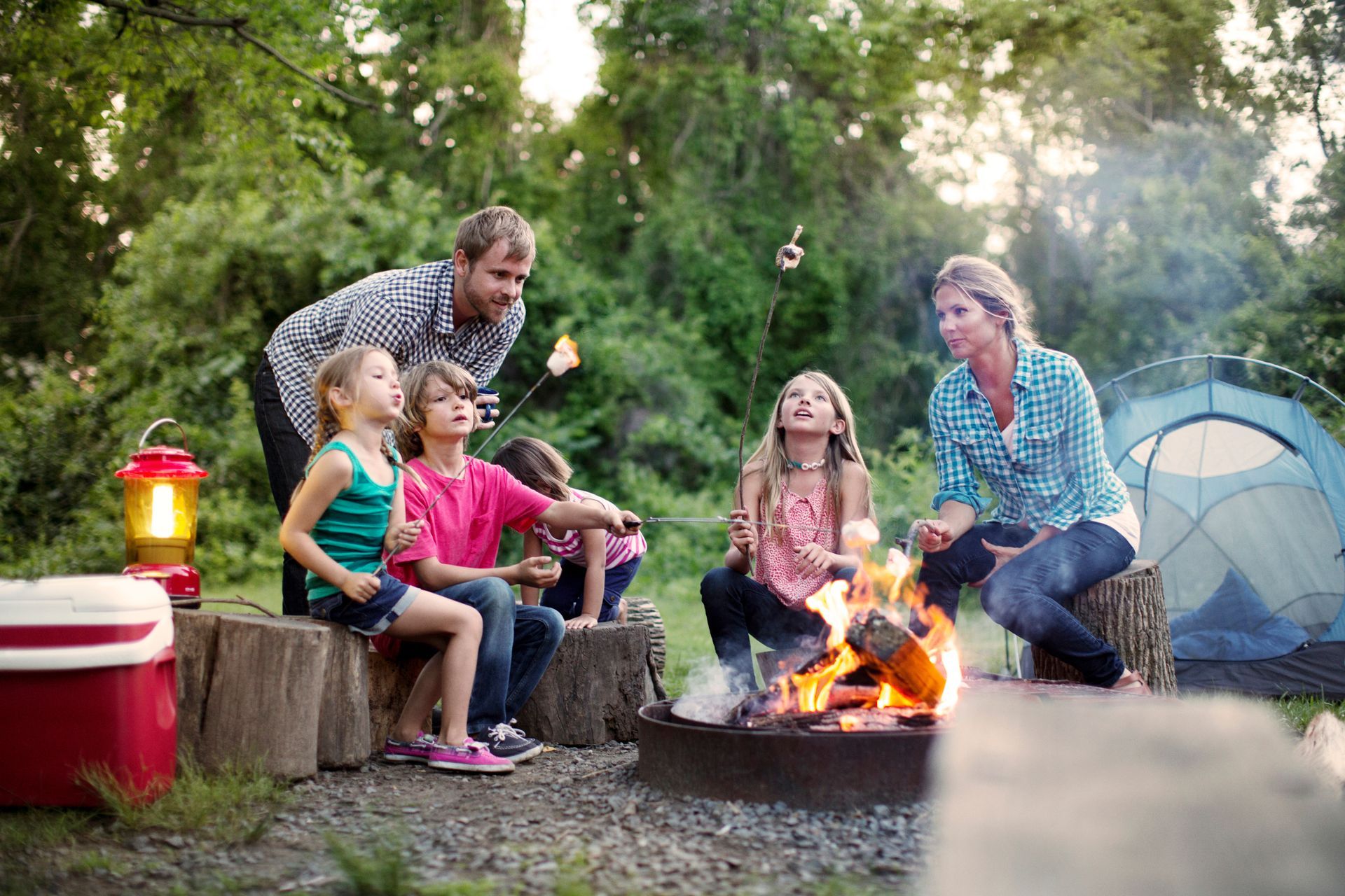 A family is sitting around a campfire roasting marshmallows.