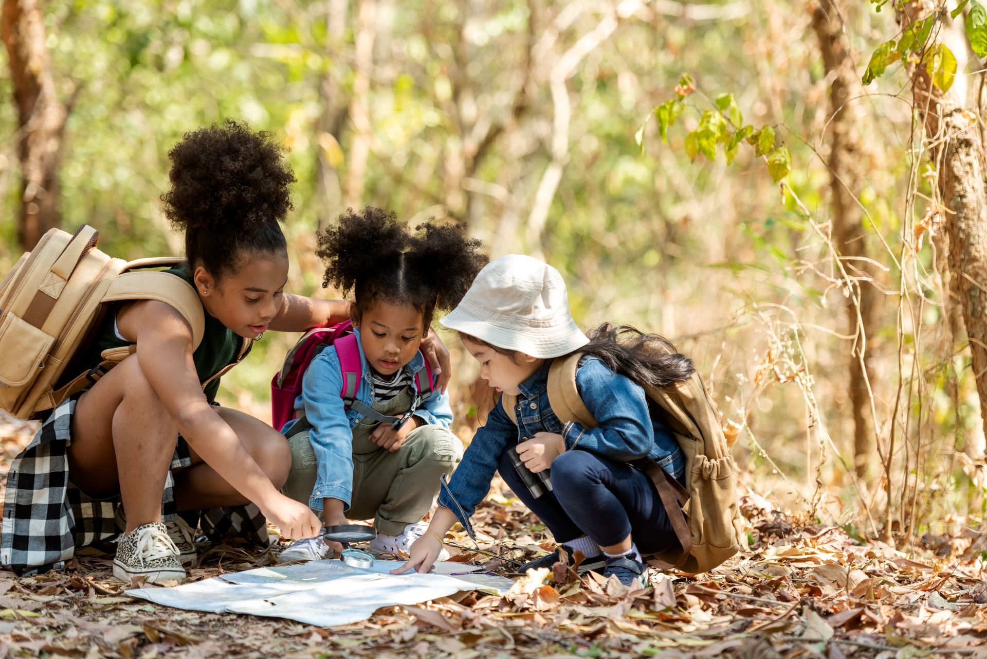 A group of children are looking at a map in the woods.