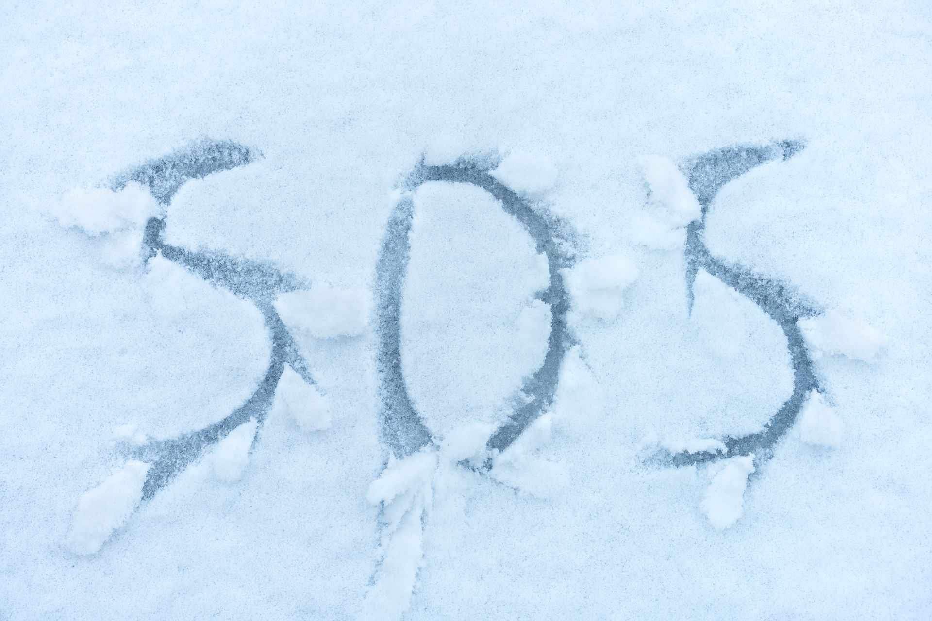 The word sos is written in the snow.