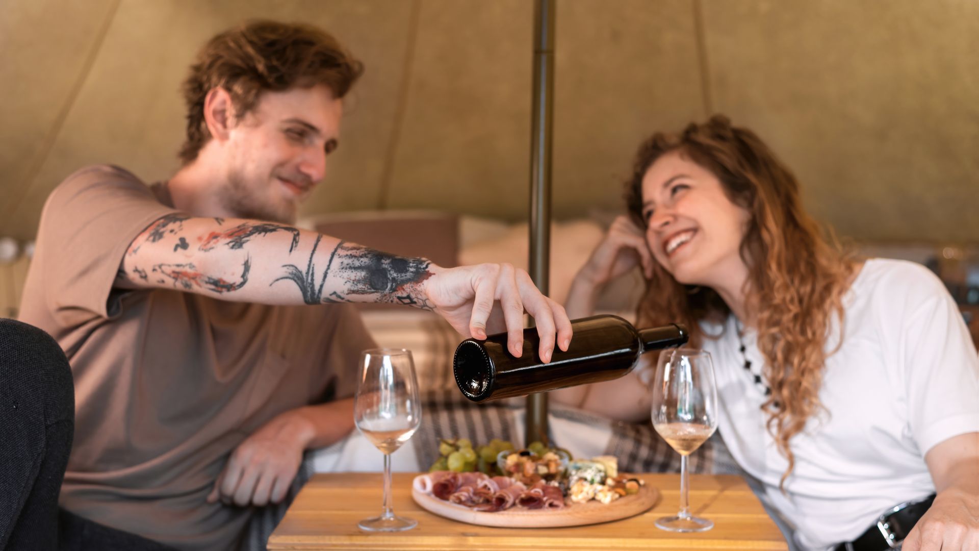 A man is pouring wine into a woman 's glass at a table.