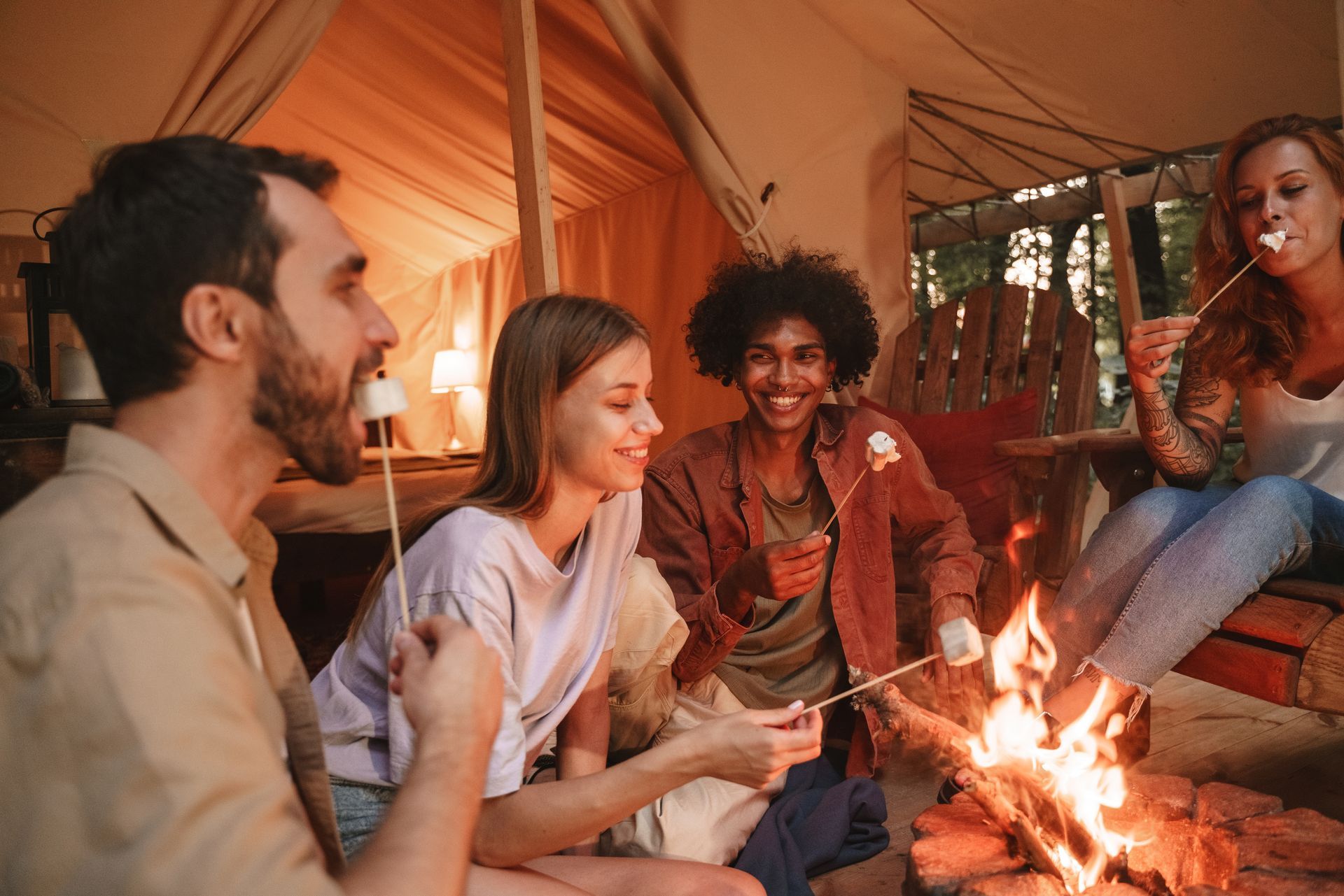 A group of people are sitting around a campfire eating marshmallows.