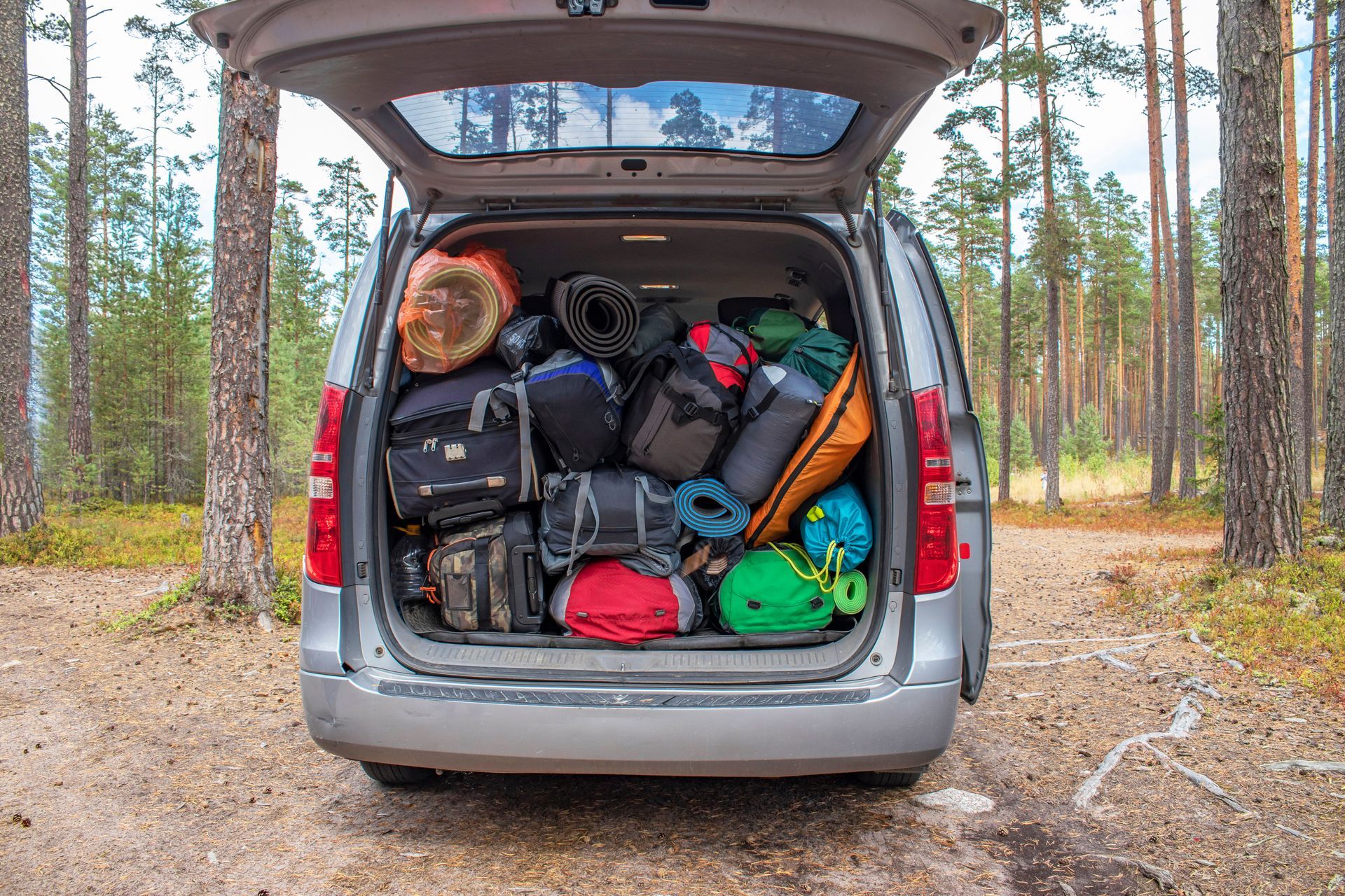 The back of a van is filled with luggage and sleeping bags.