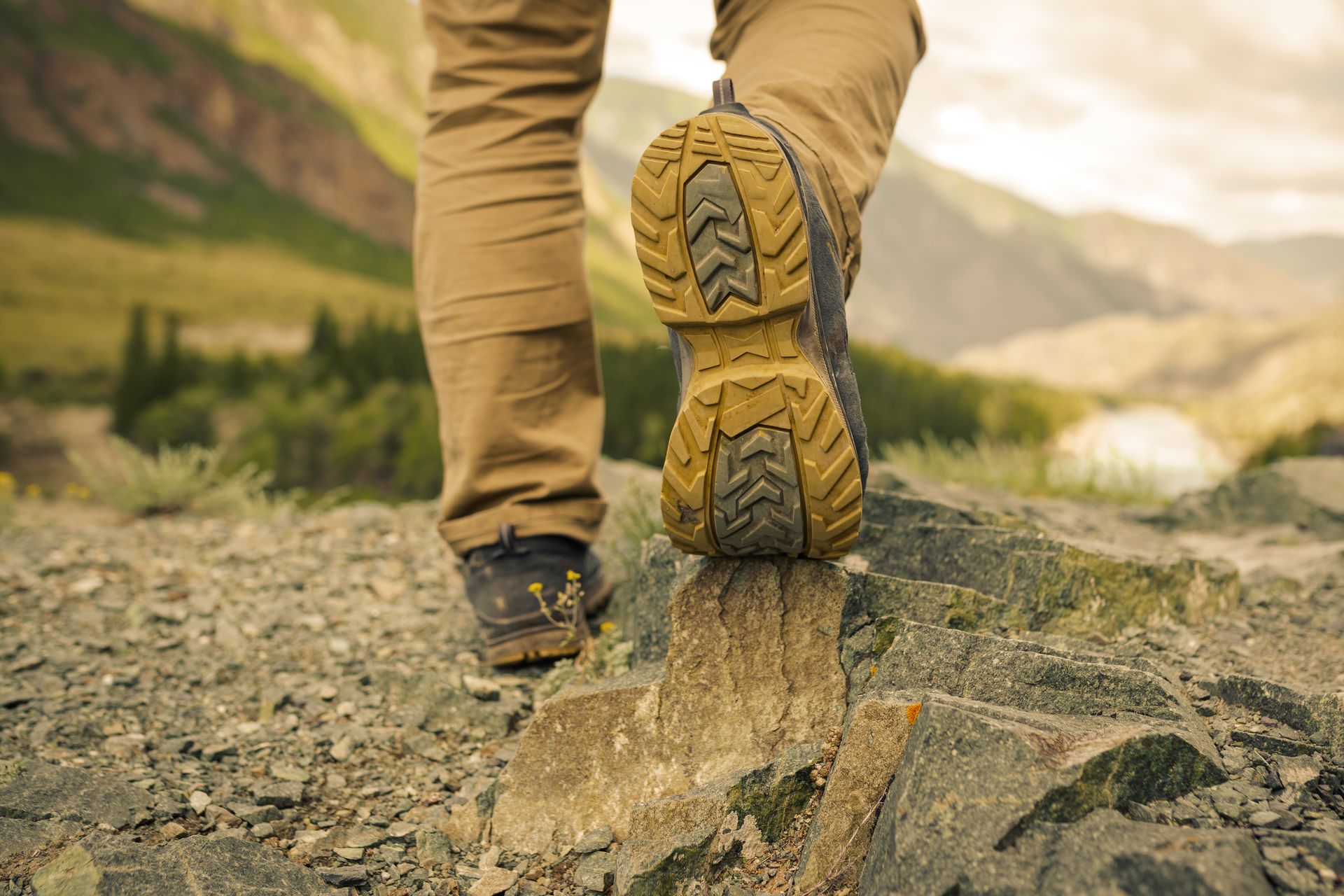 A person is walking on a rocky trail in the mountains.