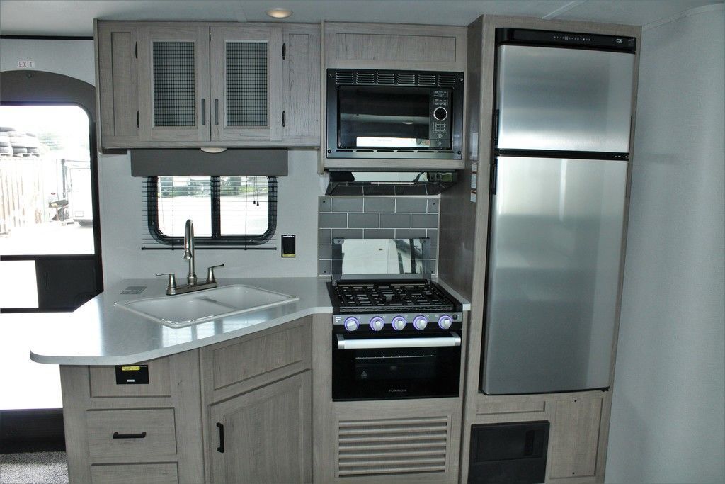 A kitchen with a stove , sink , refrigerator and microwave