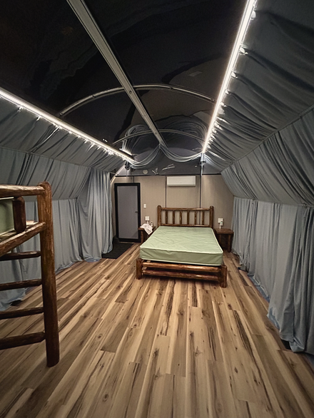 Attic bedroom with gray draped walls, striped wood floor, and a bed under slanted skylights