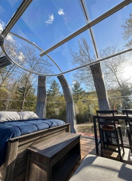 Attic bedroom with gray draped walls, striped wood floor, and a bed under slanted skylights