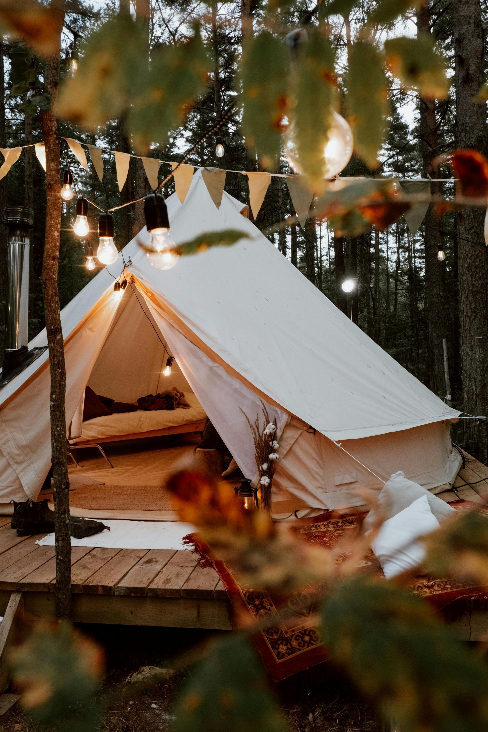 A tent is sitting on a wooden deck in the middle of a forest.