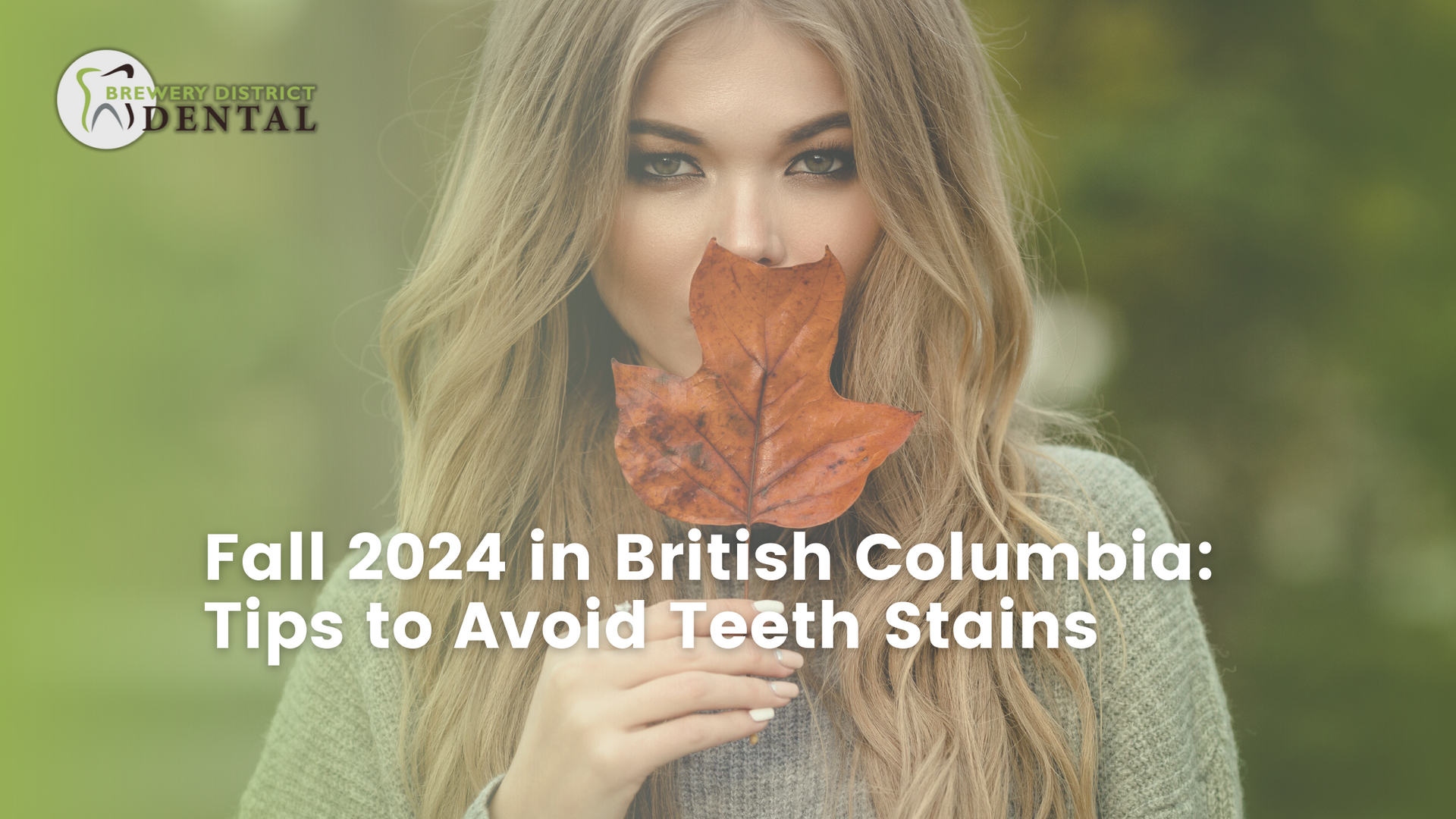 A woman is holding a maple leaf in front of her mouth.