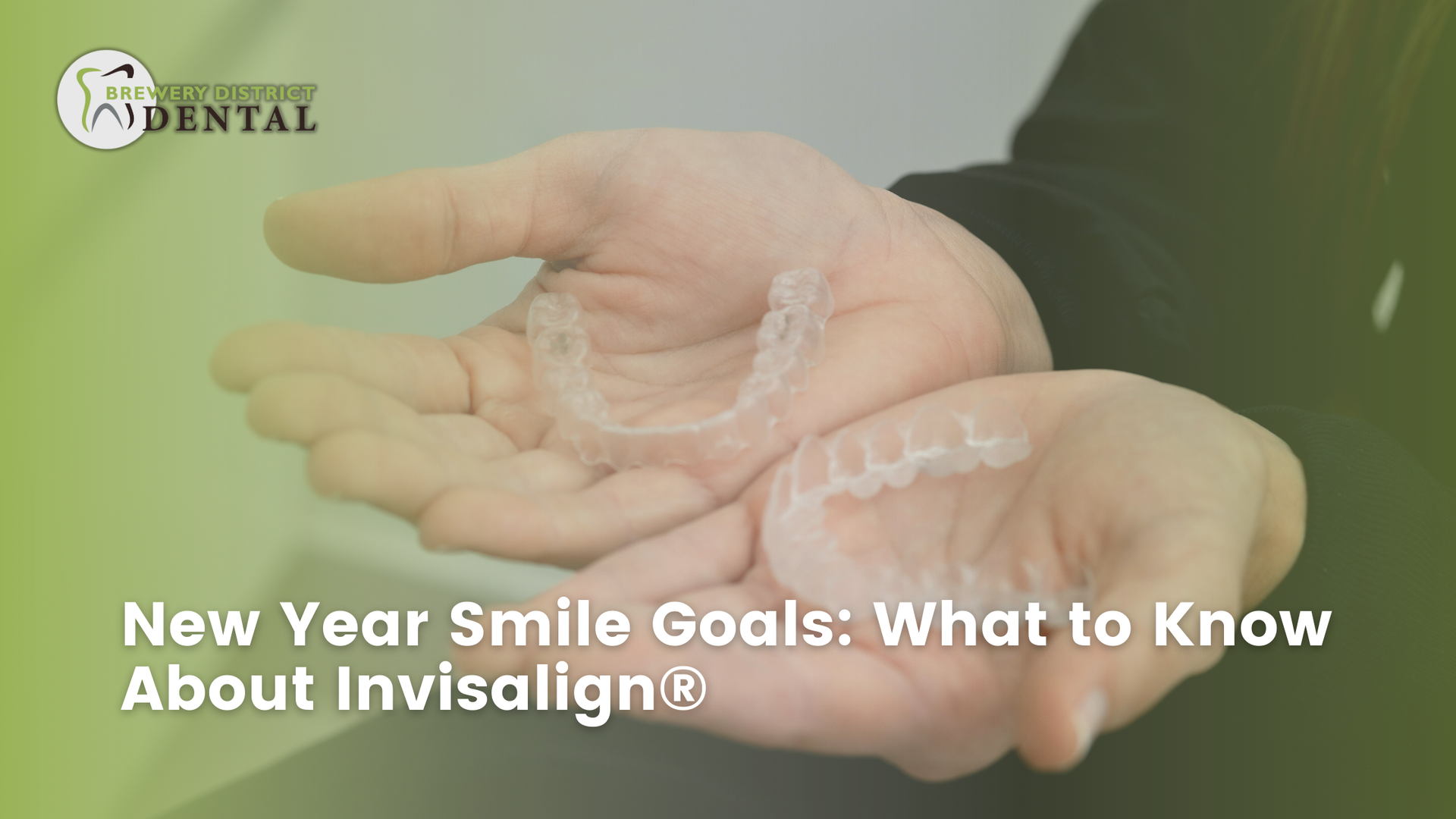 Hands holding clear Invisalign aligners, promoting smile goals for the new year.