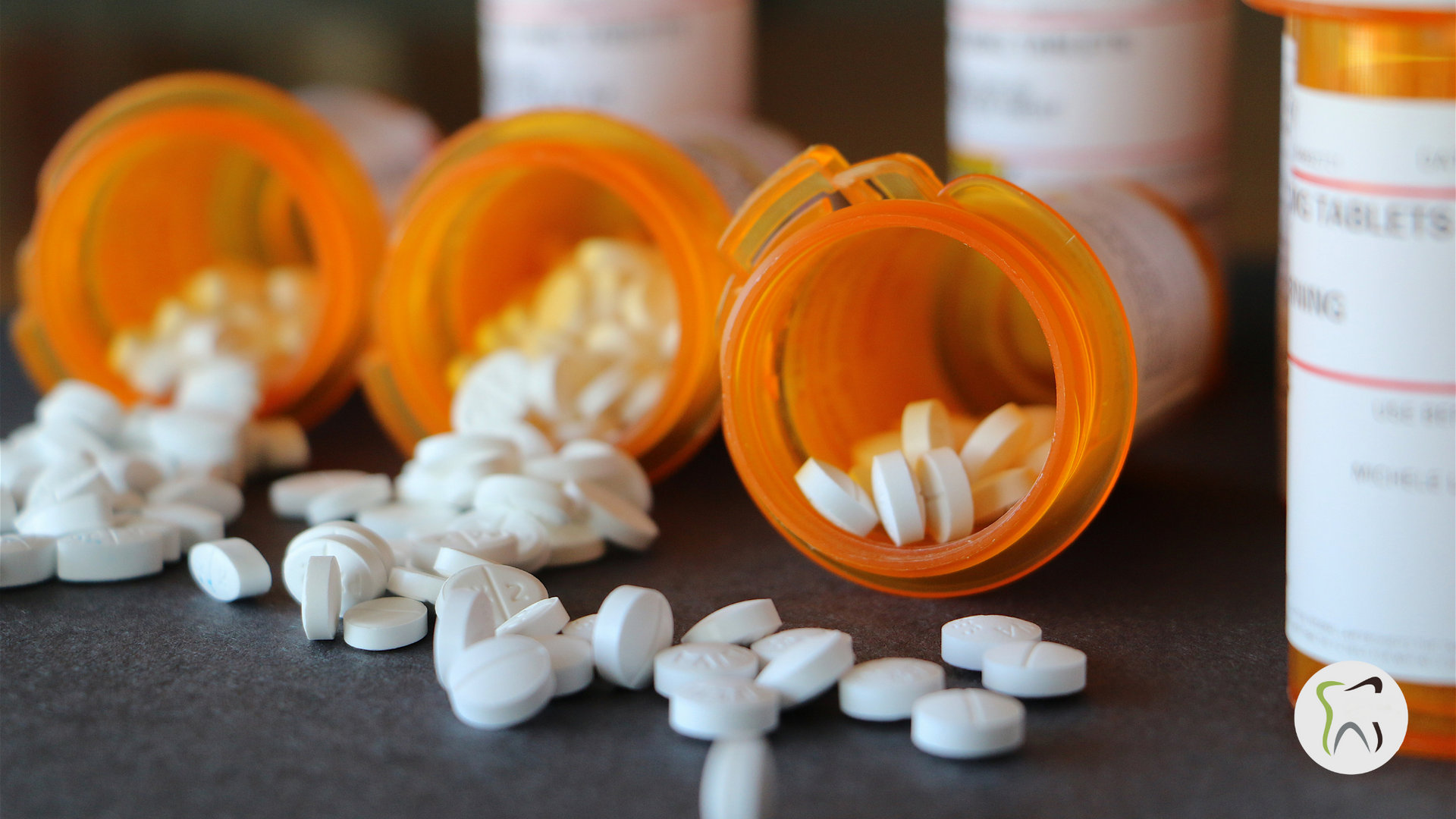 A bunch of pills are spilling out of bottles on a table.