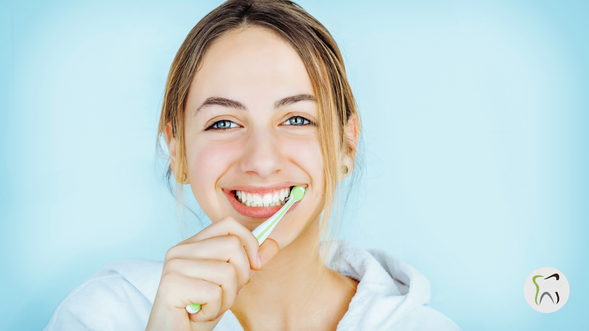 A woman is brushing her teeth with a green toothbrush.