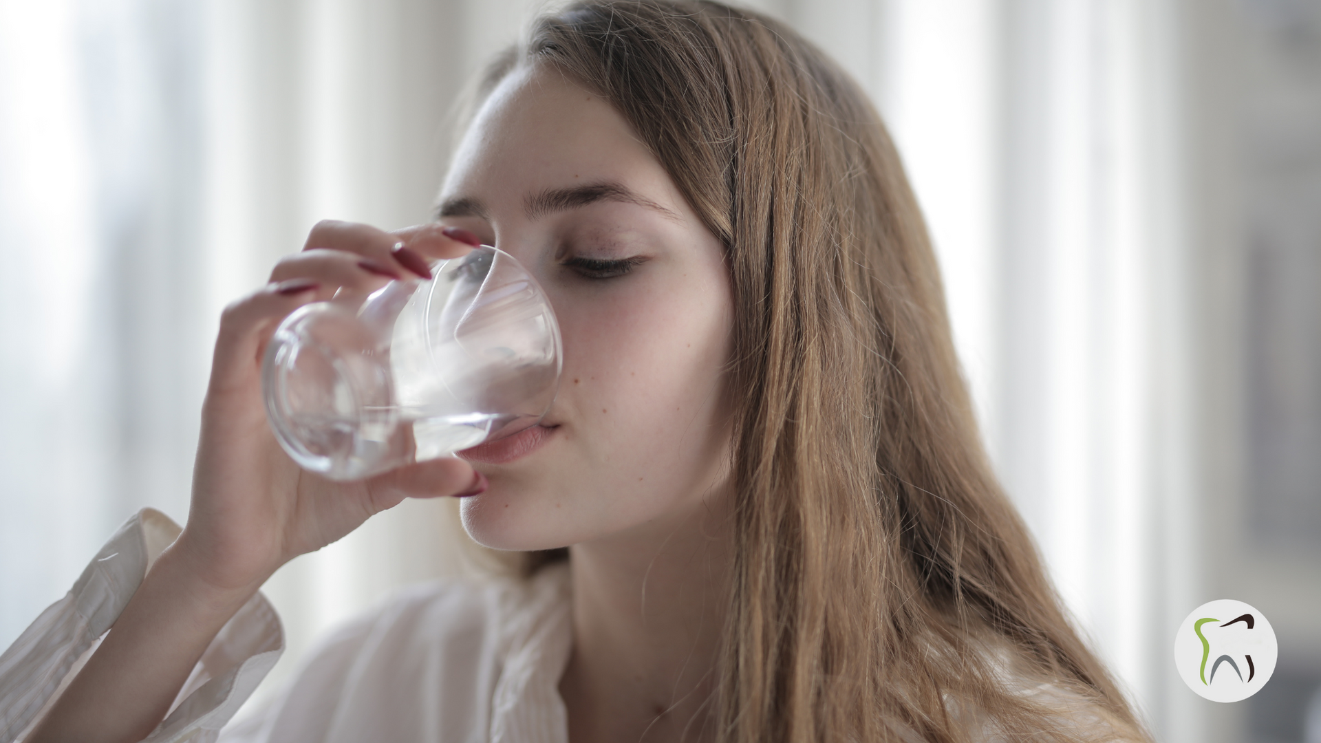 A woman is drinking water from a glass.