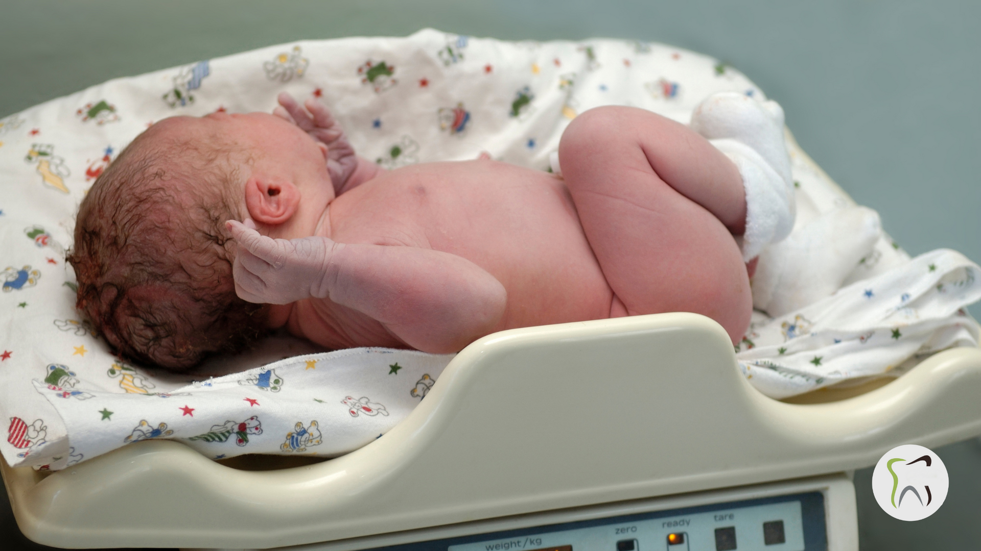 A newborn baby is laying on a scale.