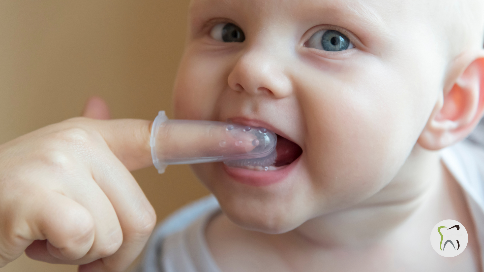 A baby is brushing his teeth with a finger toothbrush.