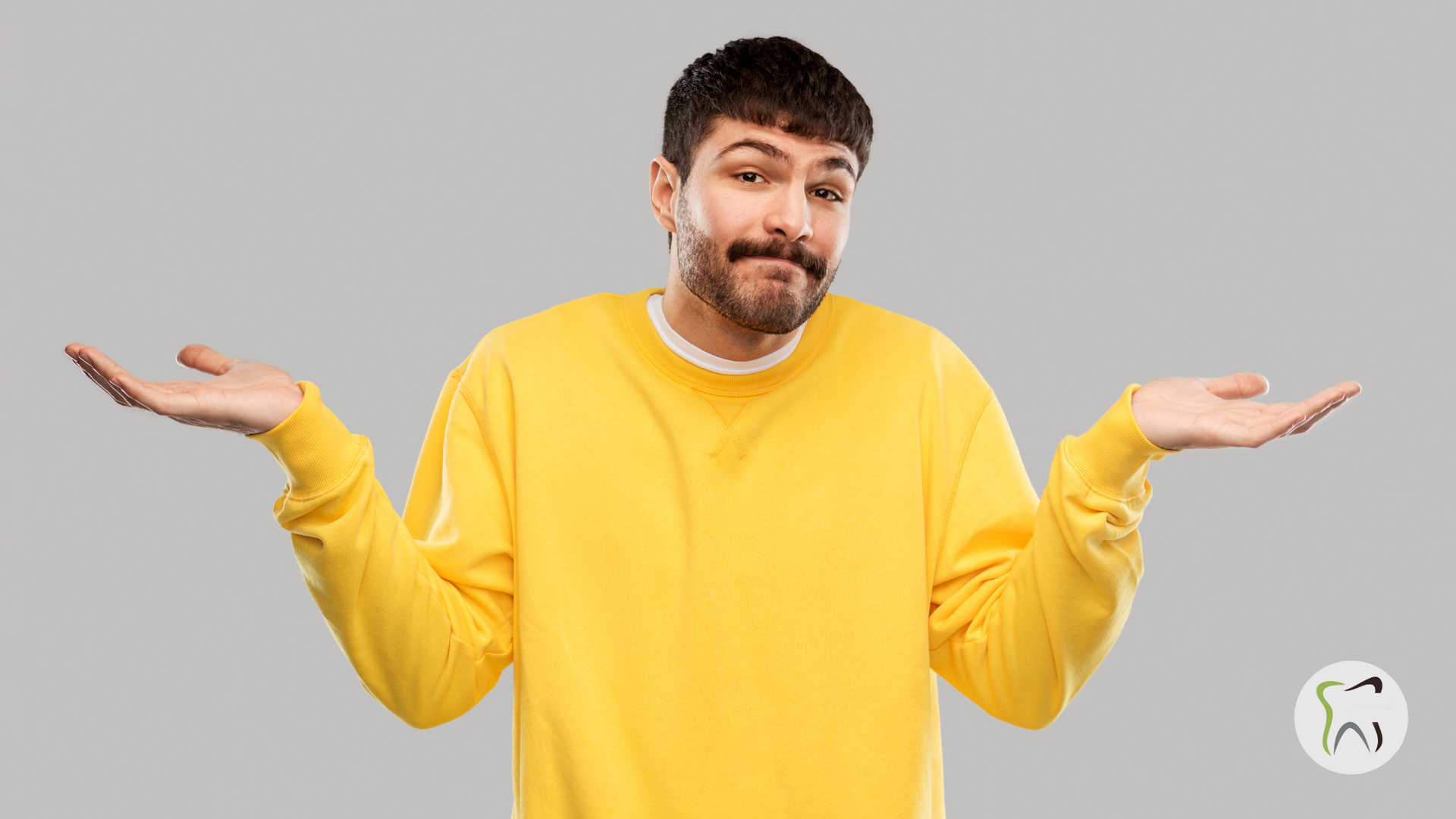 A man in a yellow sweater is shrugging his shoulders.