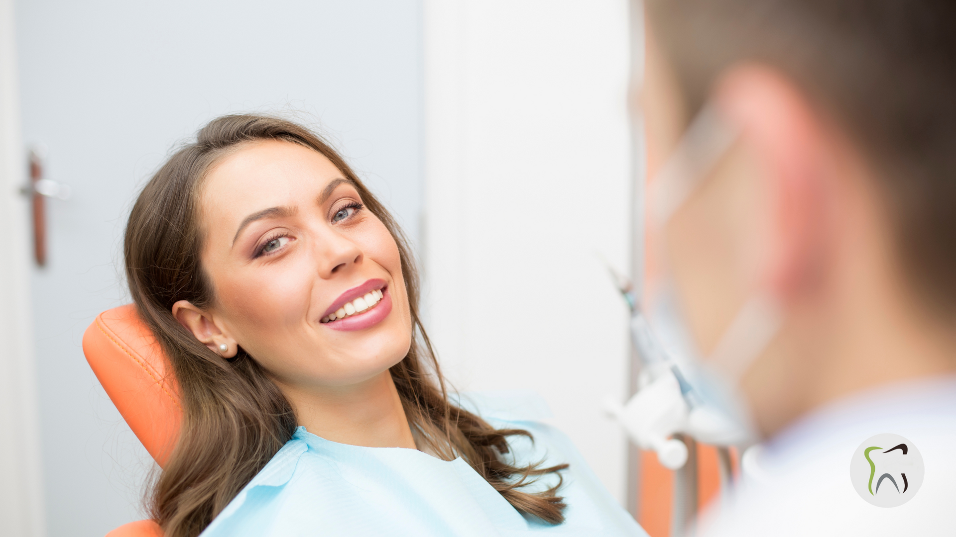 A woman is sitting in a dental chair smiling at the dentist.