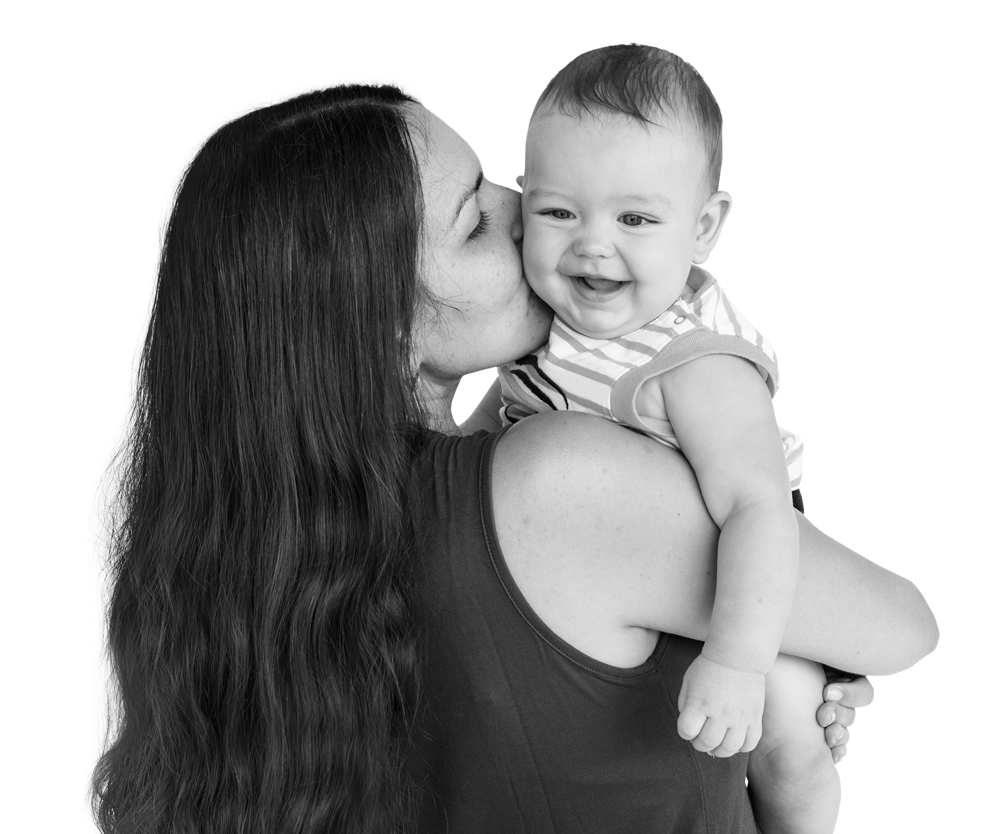 Woman kissing smiling baby held in her arms. Woman kissing smiling baby held in her arms.