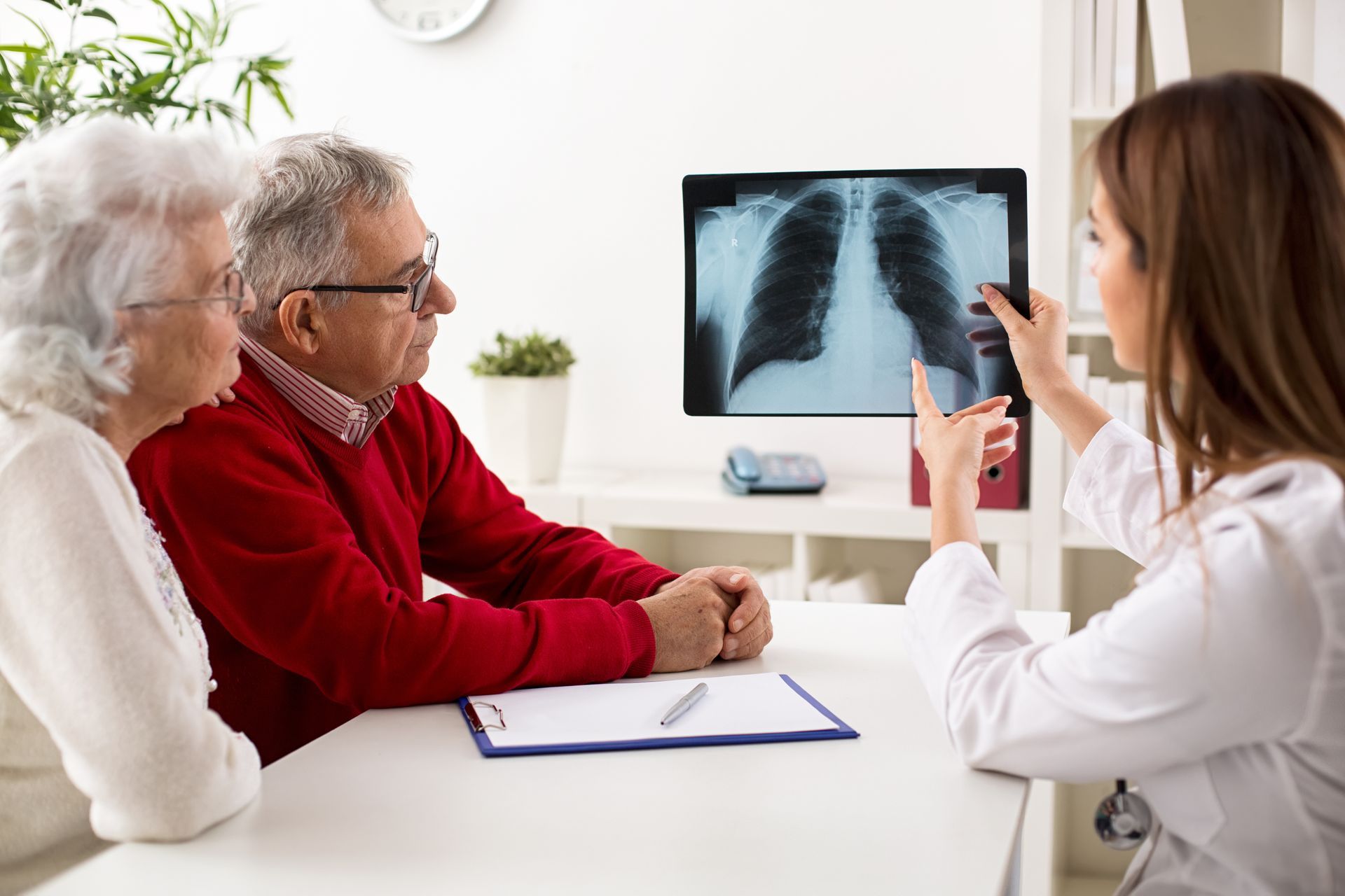 Doctor showing a chest X-ray to a senior couple in a medical office. Doctor showing a chest X-ray to a senior couple in a medical office.