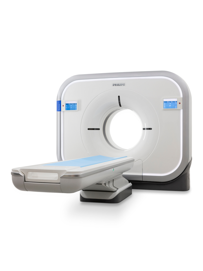 A person operates computer monitors in a medical office, with a CT scanner visible in the background. A person operates computer monitors in a medical office, with a CT scanner visible in the background.