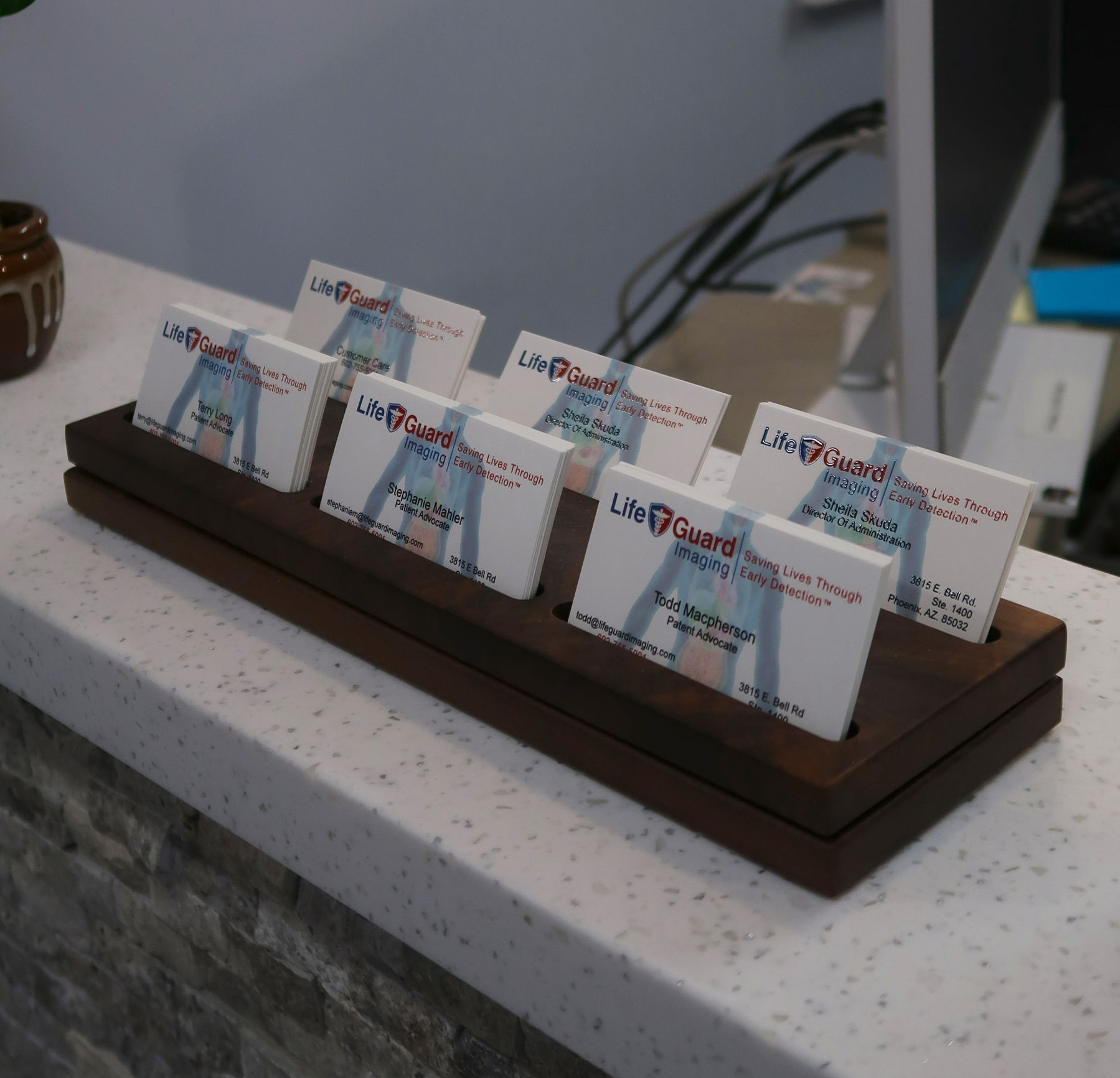 Sign for Orion Center with company names: FRCC, Anchor Glass, and UltraGuard Imaging, with red flowers. Sign for Orion Center with company names: FRCC, Anchor Glass, and UltraGuard Imaging, with red flowers.