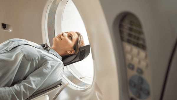 Woman undergoing a CT scan, lying on a table inside a large medical machine.