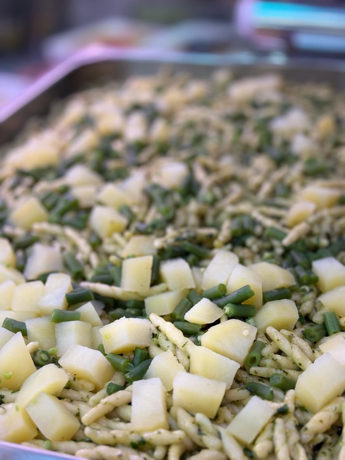 Primo piano di un vassoio di cibo con tagliatelle, fagiolini e patate.