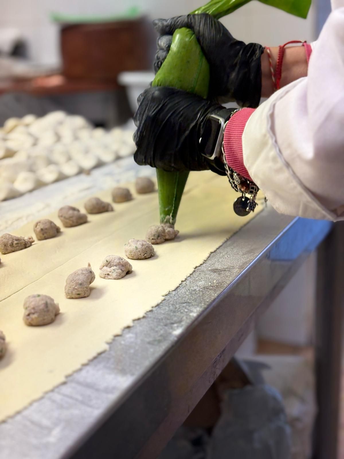 Una persona sta preparando degli gnocchi su un tavolo con un sacchetto verde.