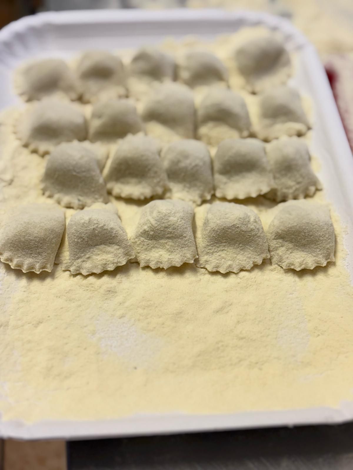 Un vassoio di ravioli infarinati su un tavolo.