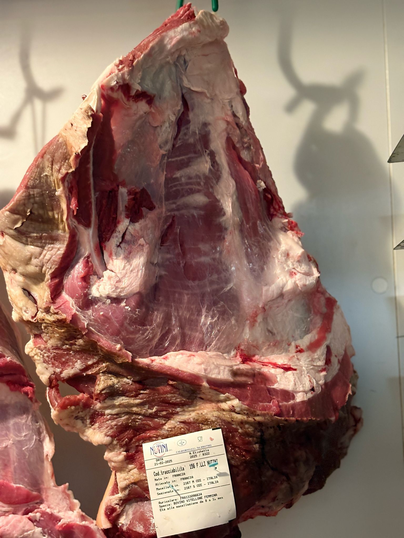 Un pezzo di carne è appeso a un gancio con un'etichetta sopra.