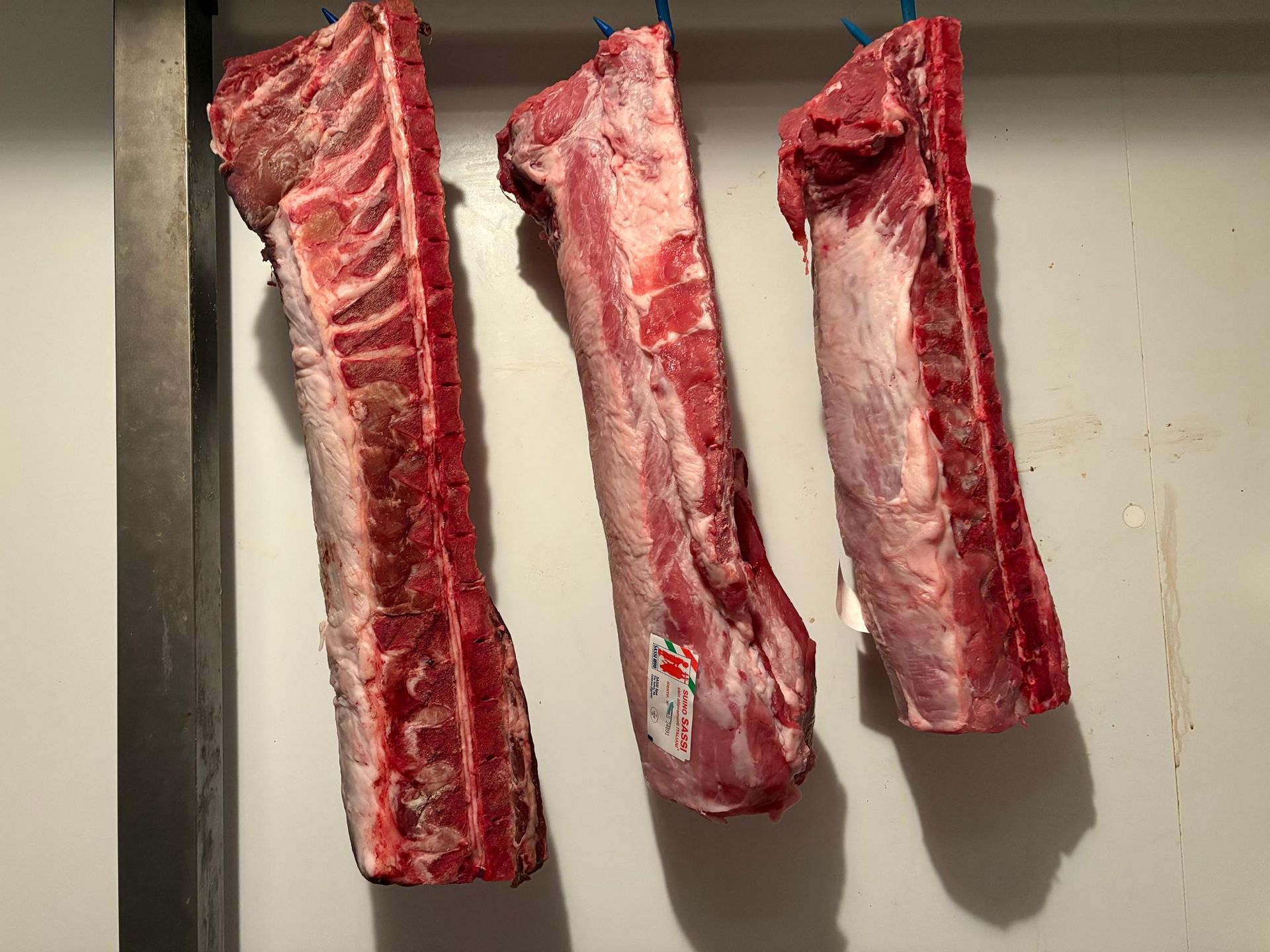 Tre pezzi di carne cruda sono appesi a una gruccia.