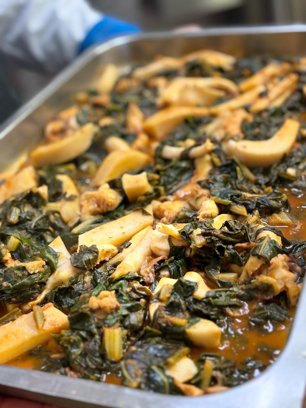 Una persona tiene in mano un vassoio di cibo con verdure e carne.