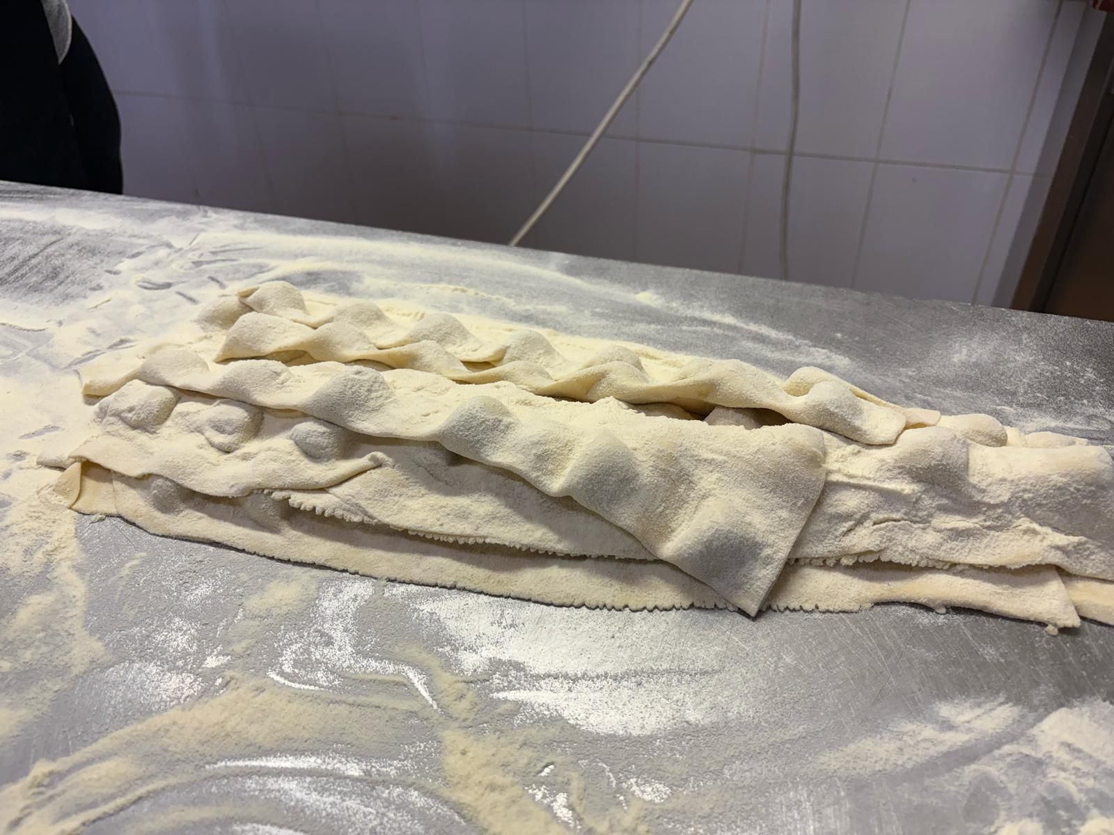 Un pezzo di pasta è appoggiato su un tavolo ricoperto di farina.