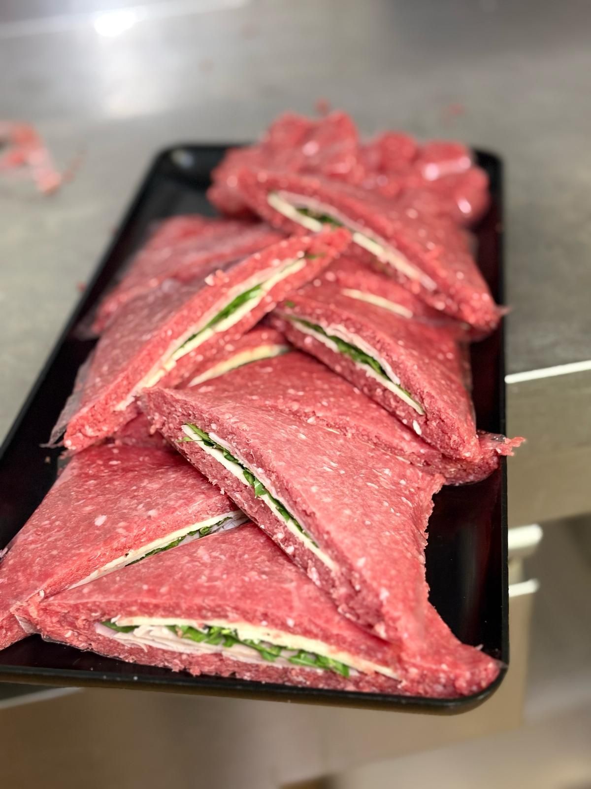 Un vassoio di panini alla carne su un tavolo.