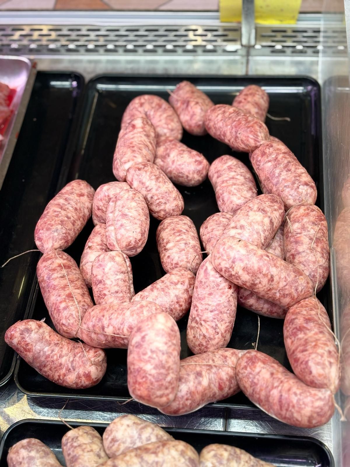 Un mucchio di salsicce è appoggiato su un vassoio nero.