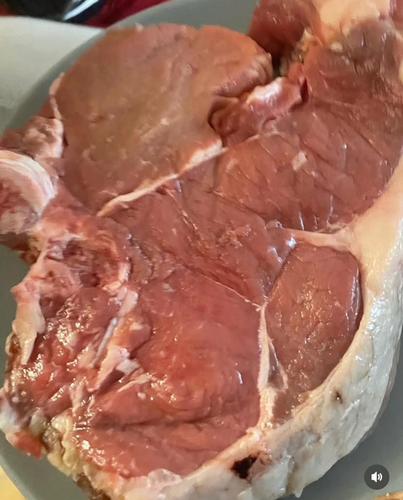 Un grosso pezzo di carne cruda è su un piatto.