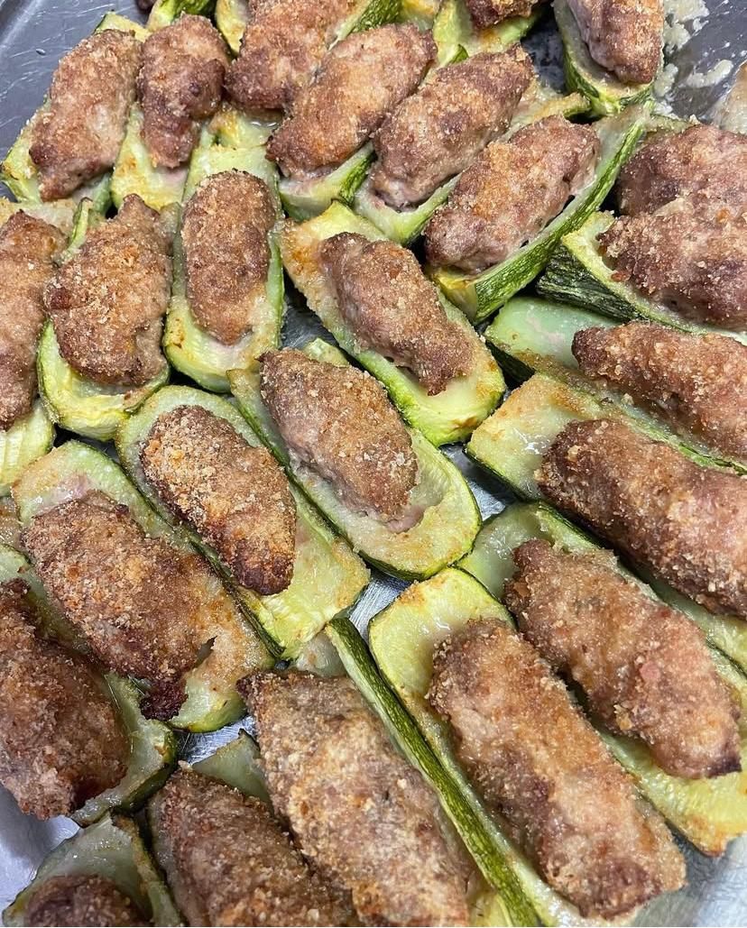 Primo piano di un piatto di zucchine ripiene di carne su un tavolo.
