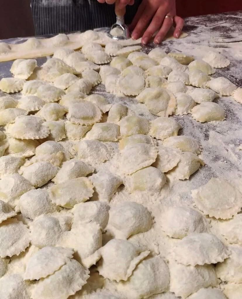 Una persona sta preparando i ravioli su un tavolo ricoperto di farina