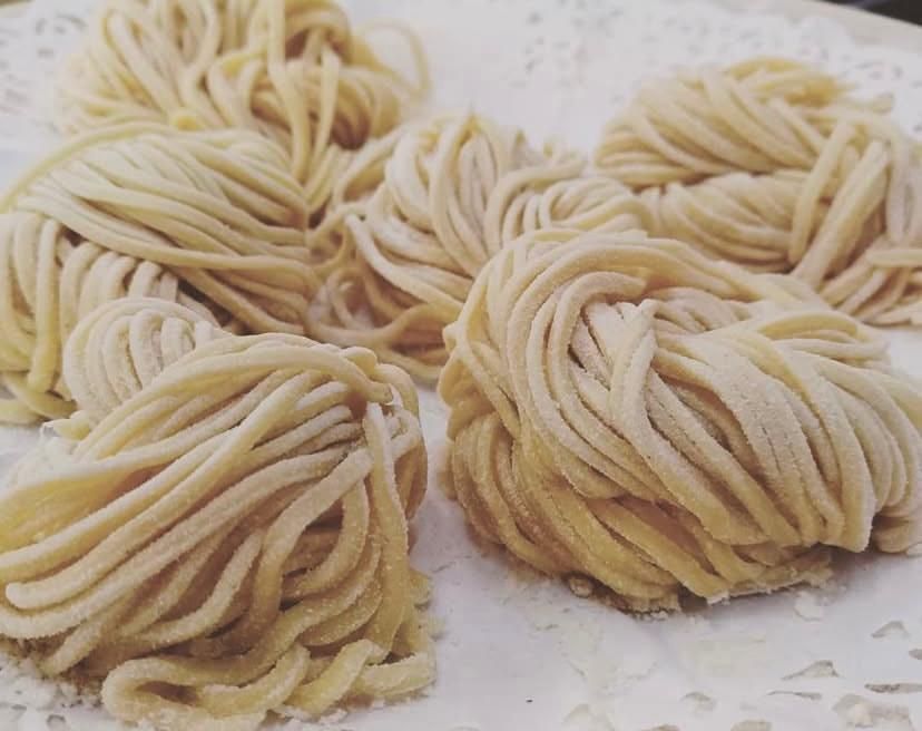 Un mucchio di tagliatelle è appoggiato su un piatto bianco.