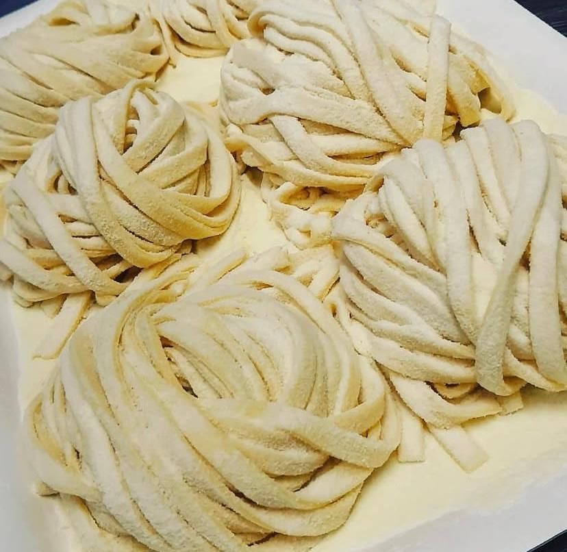 Un piatto bianco sormontato da un mucchio di tagliatelle