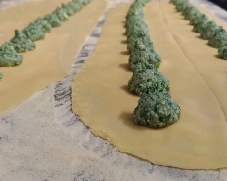 Un primo piano di un pezzo di pasta con ripieno verde sopra