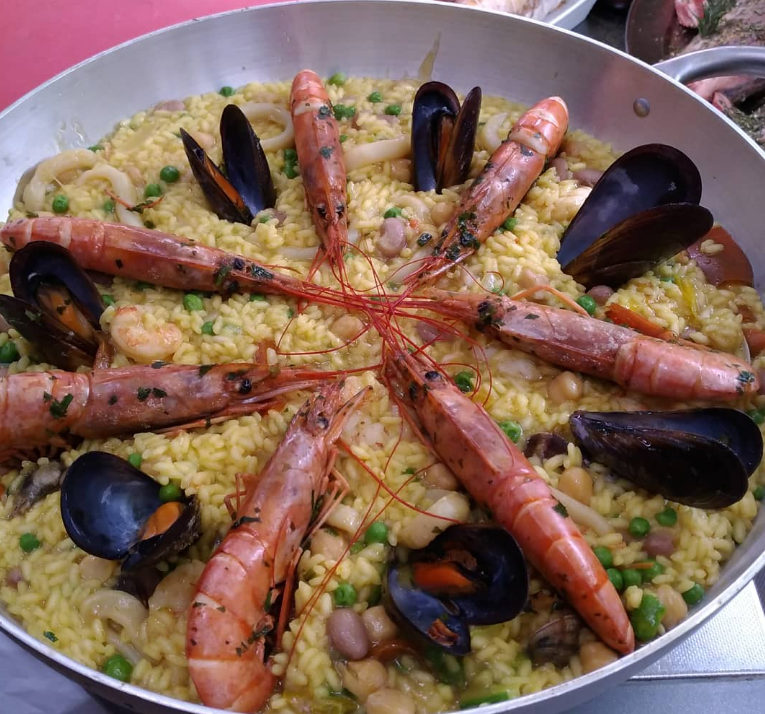 Una padella di paella di pesce con gamberi, cozze e piselli